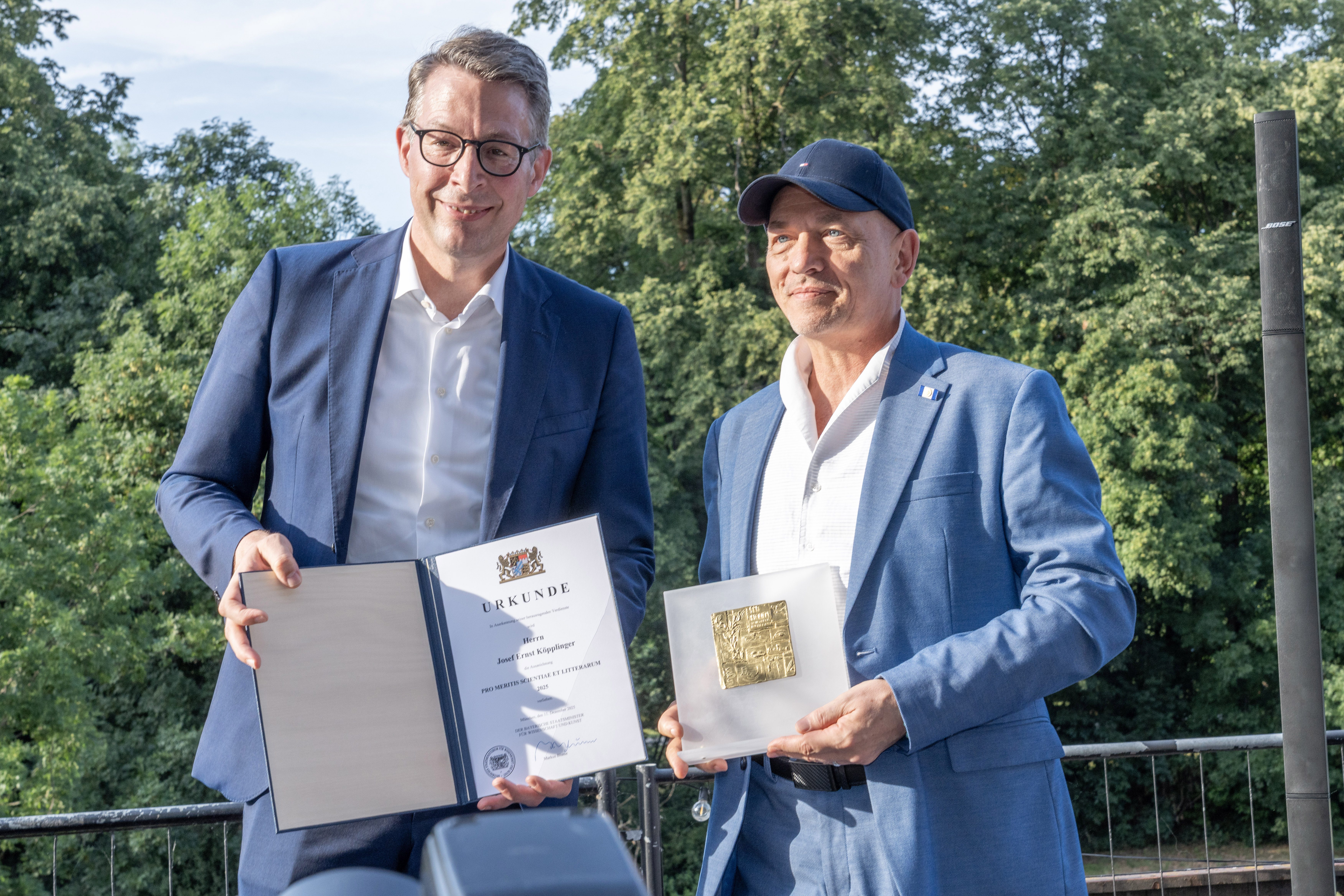 Staatsminister Markus Blume überreicht Josef E. Köpplinger die Auszeichnung PRO MERITIS SCIENTIAE ET LITTERARUM